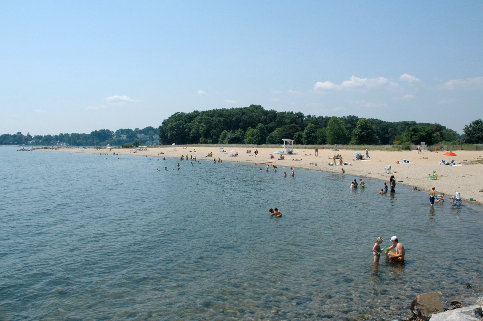 West Beach at Sherwood Island State Park in summer, swimmers in calm water along a curving sandy shore